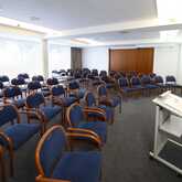 A well-lit seminar room with rows of blue chairs and a podium at the front is ready for a presentation.