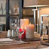 A cozy restaurant table is elegantly set with glowing candles and neatly arranged wine glasses.