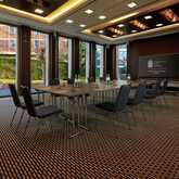 A modern conference room at Wasserturm Hotel with a large table and chairs is set up for a meeting.