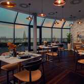 A chic private dining room offers a panoramic city view through large windows, creating an elegant atmosphere.