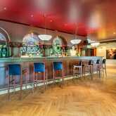 Eine elegante Bar mit roten Decken, hohen Stühlen und dekorativen Leuchten lädt zum Verweilen ein.