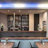 Eine stilvolle Hotelbar mit modernem Design zeigt Regale voller Flaschen, einen Tresen und gemütliche Sitzgelegenheiten.