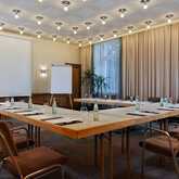 Ein leerer Konferenzraum mit U-förmigem Tisch, Stühlen, Flipchart und Projektionsleinwand, bereit für ein Geschäftstreffen.