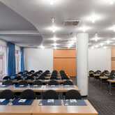 A modern conference room is set up with rows of tables and chairs, ready for a meeting.