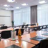 A modern conference room with neatly arranged tables and chairs, ready for a meeting with notepads and bottled water.