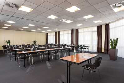 A spacious meeting room in Varresbeck features neatly arranged tables and chairs, ready for a conference or seminar.