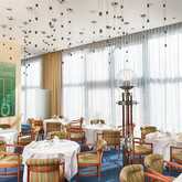 A stylish restaurant with patterned chairs and elegantly set tables under modern pendant lighting.