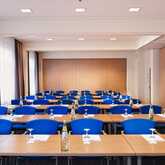 Ein Konferenzraum mit blauen Stühlen und Tischen ist für ein Meeting vorbereitet, mit Wasserflaschen und Gläsern.