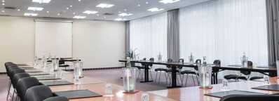 A modern conference room with a U-shaped table setup, ready for a meeting with notepads and water bottles.