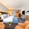 Ein modernes Hotelzimmer mit zwei Betten, gemütlichen Sesseln und einer stilvollen Wanddekoration lädt zum Entspannen ein.