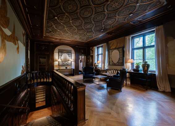 Ein elegant gestaltetes Zimmer mit kunstvoller Decke und stilvollen Möbeln bietet eine einladende Atmosphäre.