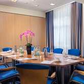 Ein Konferenzraum mit blau gepolsterten Stühlen, einem Tisch, Orchideen und Getränken ist für ein Meeting vorbereitet.
