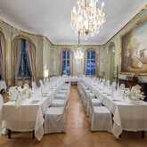 Ein elegantes Musikzimmer mit langen, gedeckten Tafeln und einem großen Kronleuchter, das für ein formelles Dinner vorbereitet ist.