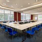 A spacious conference room with U-shaped tables and blue chairs set up for a meeting at Wyndham Garden.
