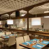 A modern restaurant with neatly set tables and soft lighting offers a cozy dining experience.