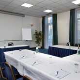 A meeting room is arranged with U-shaped tables, notepads, and water bottles, ready for a conference session.