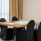 A neatly arranged meeting room in Breitenberg features a table set for four with black chair covers and glassware.