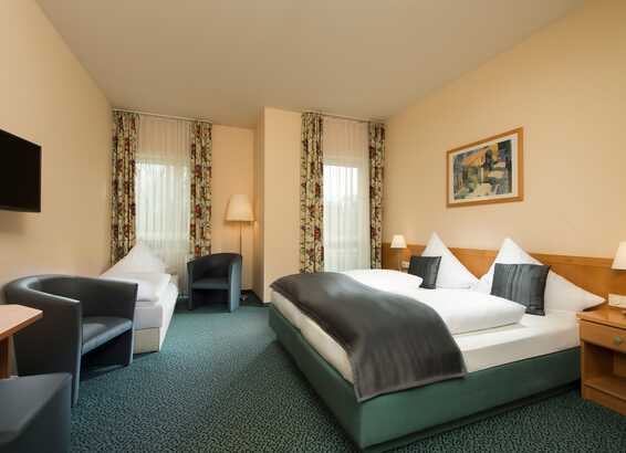A spacious double room features a large bed, modern decor, and comfortable seating, perfect for a relaxing stay at the Residenz.