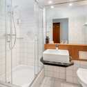 A modern bathroom features a glass shower enclosure, square sink, and bright lighting, creating a clean and elegant space.