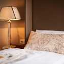 Ein stilvolles Bett mit elegantem Kissen steht neben einer leuchtenden Tischlampe in einem gemütlichen Schlafzimmer.