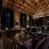Elegante Bar mit luxuriöser Einrichtung, dunklen Sofas und einem eindrucksvollen Kronleuchter im stilvollen Ambiente.