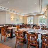 A well-lit restaurant dining area features neatly arranged wooden tables and chairs, ready for guests.