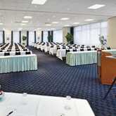 A large conference room is set up with rows of tables, chairs, and a podium, ready for a significant meeting.