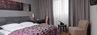 A superior hotel room features a cozy bed with a purple patterned blanket, elegant decor, and soft lighting.