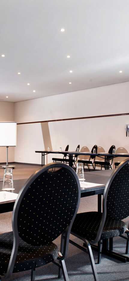An empty conference room is set up with arranged tables and chairs, ready for a business meeting.