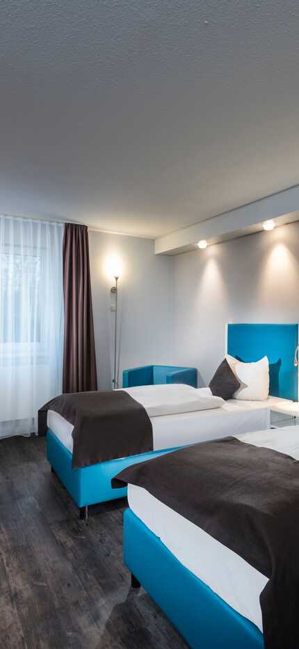 Explore the comfortable twin room at Best Western Hotel Cologne Airport Troisdorf, perfect for travelers preferring separate beds. The room offers two cozy single beds and a stylish blue armchair for added relaxation.