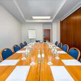 A long conference table is set with bottled water and papers in a bright meeting room at Neues Palais.