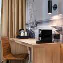 Ein moderner Holzschreibtisch mit einem eleganten Holzstuhl bietet Platz zum Arbeiten. Darauf stehen eine Kaffeemaschine mit Tassen und ein Wasserkocher.