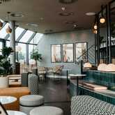 A modern lounge with stylish seating, lush plants, and large windows offering natural light and a cozy ambiance.