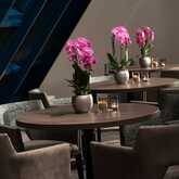 Elegante Orchideen schmücken die Tische im stilvollen Restaurantbereich eines gehobenen Hotels.