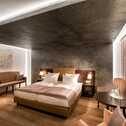 A luxurious deluxe room features a cozy bed, elegant seating, and warm lighting, perfect for a relaxing stay.