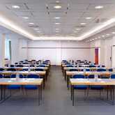 A well-lit conference room is set up with rows of tables and blue chairs, ready for the KOB21 meeting.