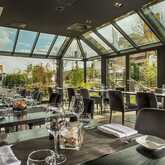 A chic restaurant with a glass roof features elegantly set tables, offering a scenic view of the cityscape outside.