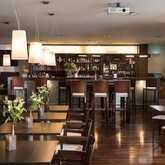 A modern hotel bar with elegant lighting, wooden furniture, and floral centerpieces creates a welcoming ambiance.