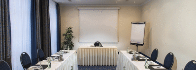 A well-lit meeting room with a U-shaped table setup, notepads, and water bottles, ready for a conference.
