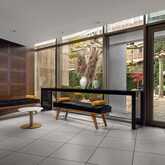 Modern breakout area with sleek benches and a view of a landscaped garden through large glass doors.
