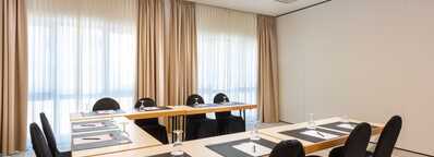 A bright meeting room in Kampenwand features arranged tables with notepads and glasses, ready for a conference.