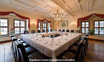 Ein elegant dekorierter Konferenzraum mit U-förmigem Tisch, gedeckt mit Gläsern und Wasserflaschen, im Stadtschloss.