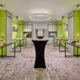 A modern foyer set up for an event features tables laden with fruit and appetizers against vibrant green walls.