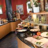 A lavish breakfast buffet features an array of meats, cheeses, and fresh vegetables in a warmly decorated dining area.
