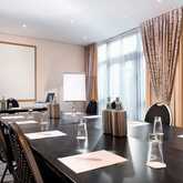 A modern conference room is set up for a meeting with notepads, water bottles, and glasses on a large table.