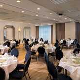 A spacious banquet room is elegantly set with round tables, white linens, and floral centerpieces, ready for an event.