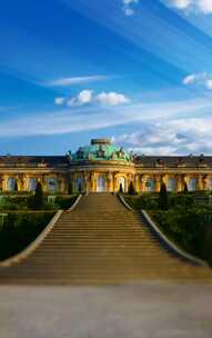 The stunning Sanssouci Castle features grand architecture surrounded by lush gardens under a clear blue sky.