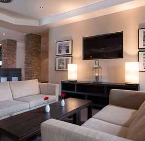 A modern hotel lobby features beige sofas, a dark wooden table, and stylish wall art, creating a welcoming atmosphere.