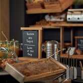 A breakfast buffet features a "Cake of the Day" sign with muffins, drinks, and a toaster on display.