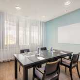 A minimalist conference room with a Bauhaus-inspired design features a sleek table, chairs, and a blank whiteboard.